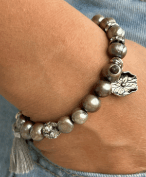 handmade dove grey pearl bracelet with crystal spacers and a sterling silver lotus flower charm with a small grey tassel on wrist